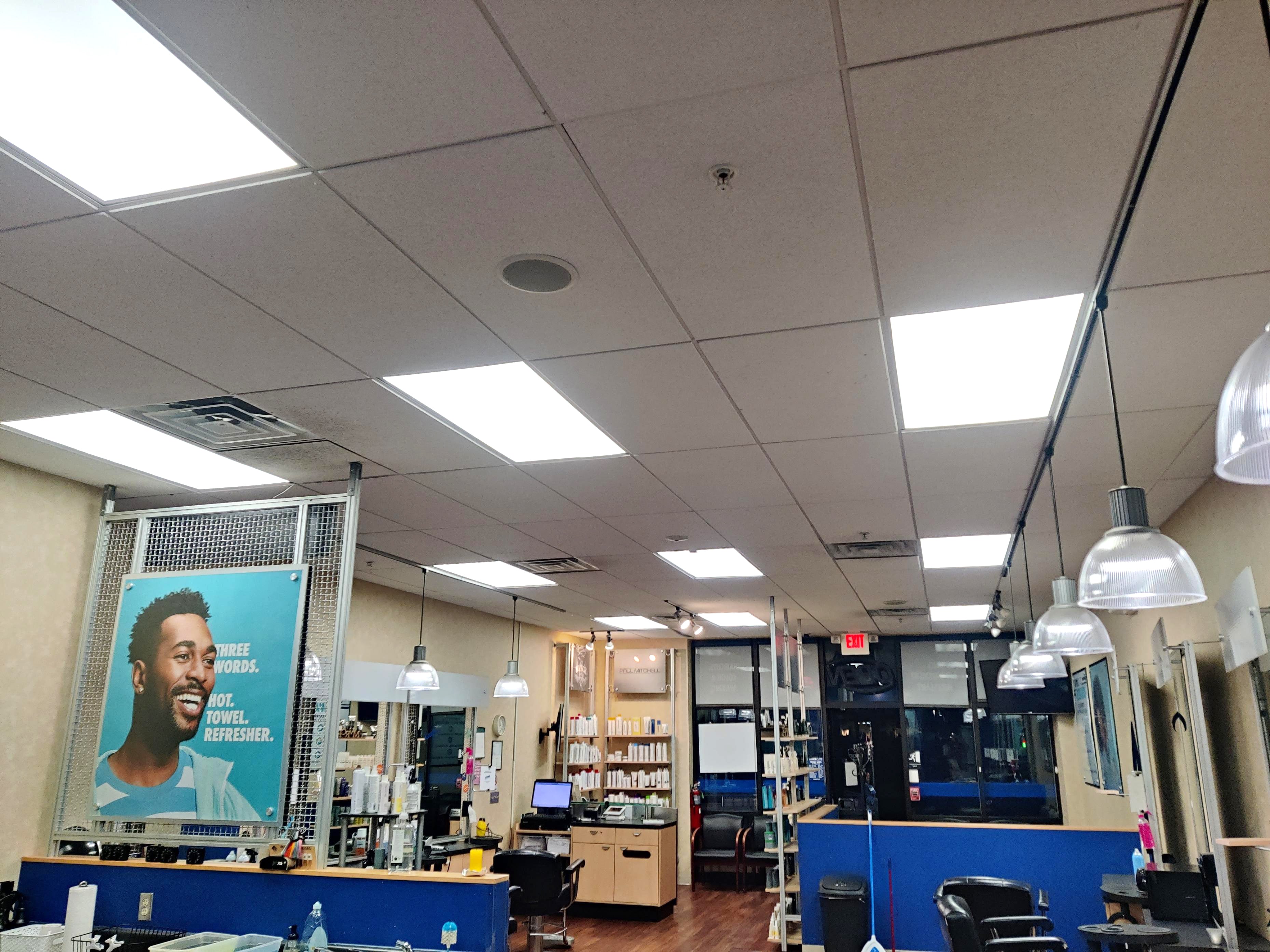 Interior view of a well-lit salon with product shelves, styling stations, and ceiling lights glowing warmly.