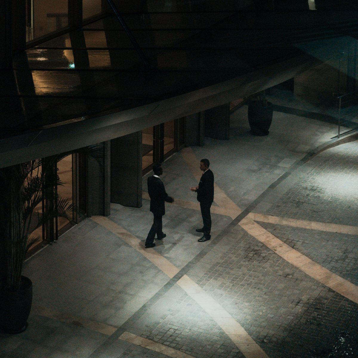 Two men talking under bright LED Canopy Light 52W MaxLite CPL Series illuminating an outdoor walkway at night