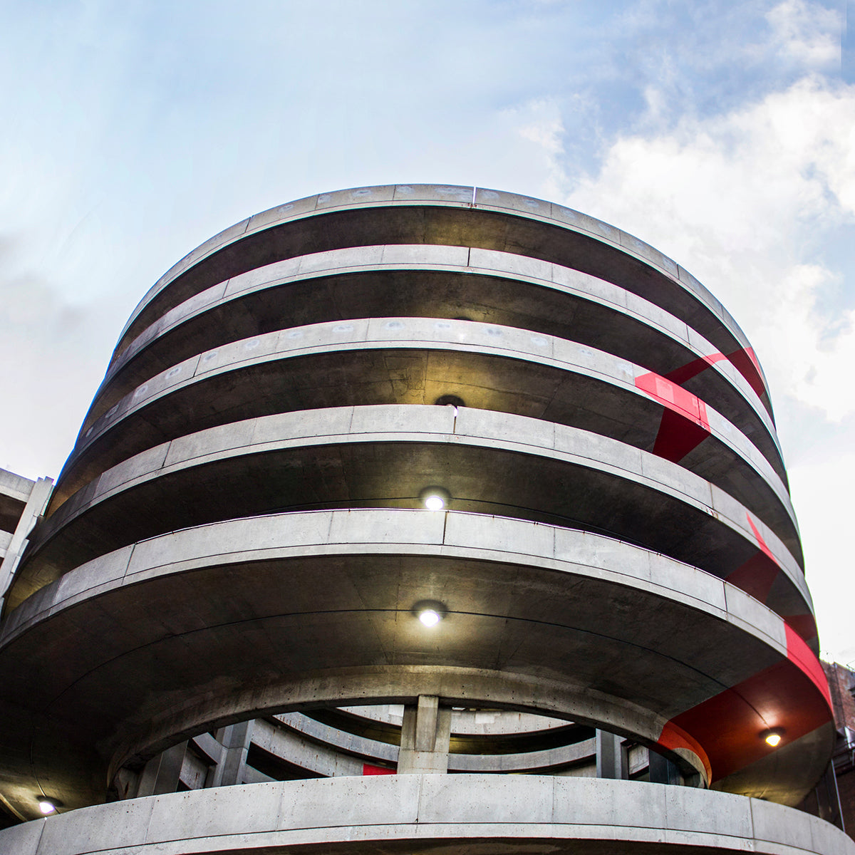 Exterior view of a circular parking garage illuminated by LED Canopy Light - 2 CCT - 60/46/36/22W fixtures at dusk