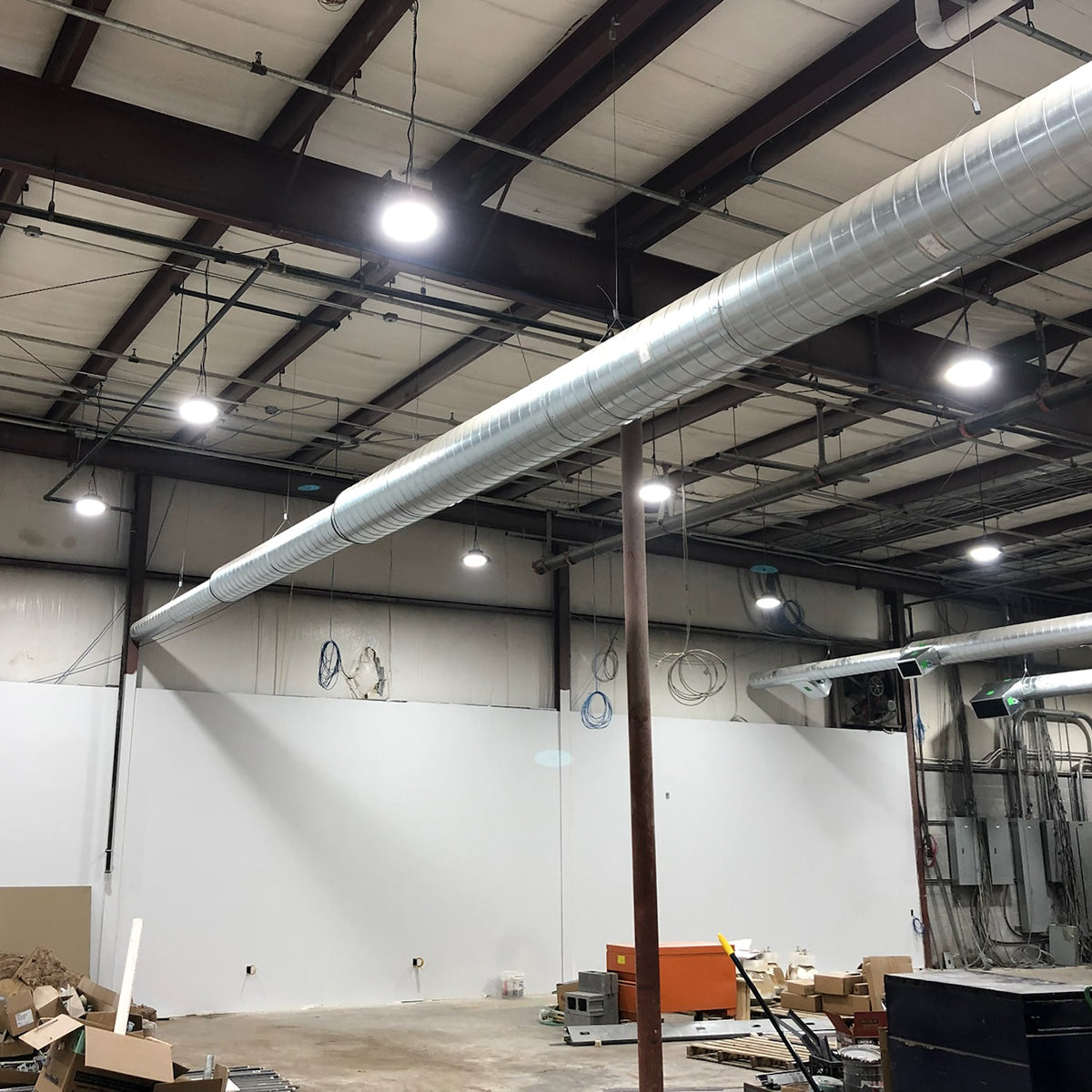 UFO LED Low Bay - 2 CCT lights mounted in industrial space with exposed ductwork and high ceilings.