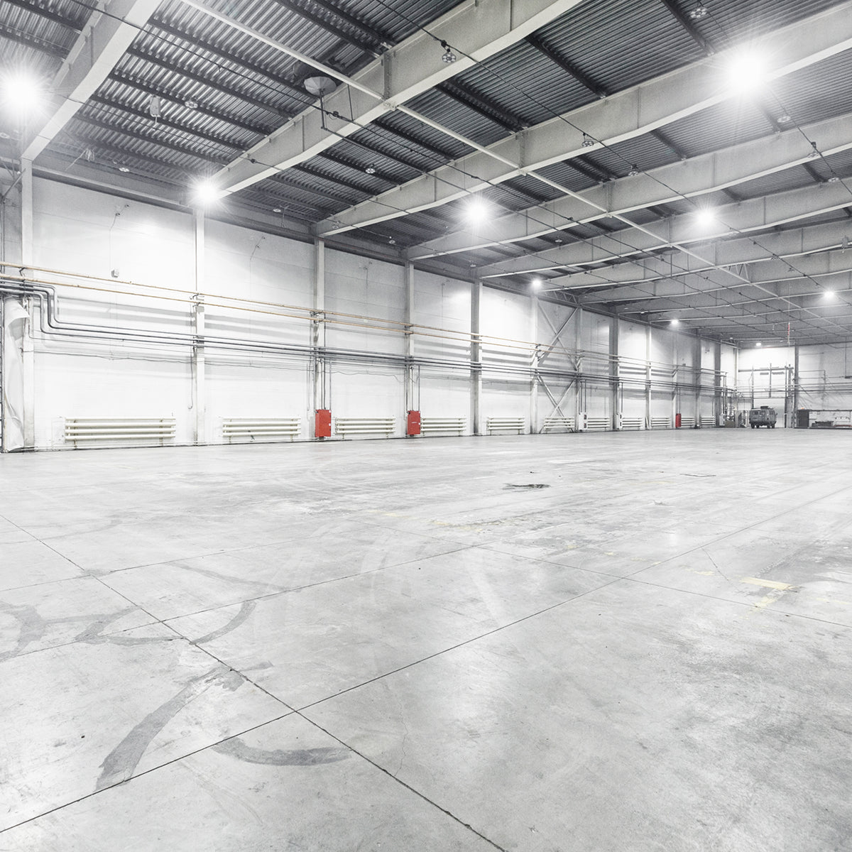Interior view of a large industrial warehouse illuminated by bright UFO LED High Bay 3-CCT MaxLite Eco Gen 3 lights