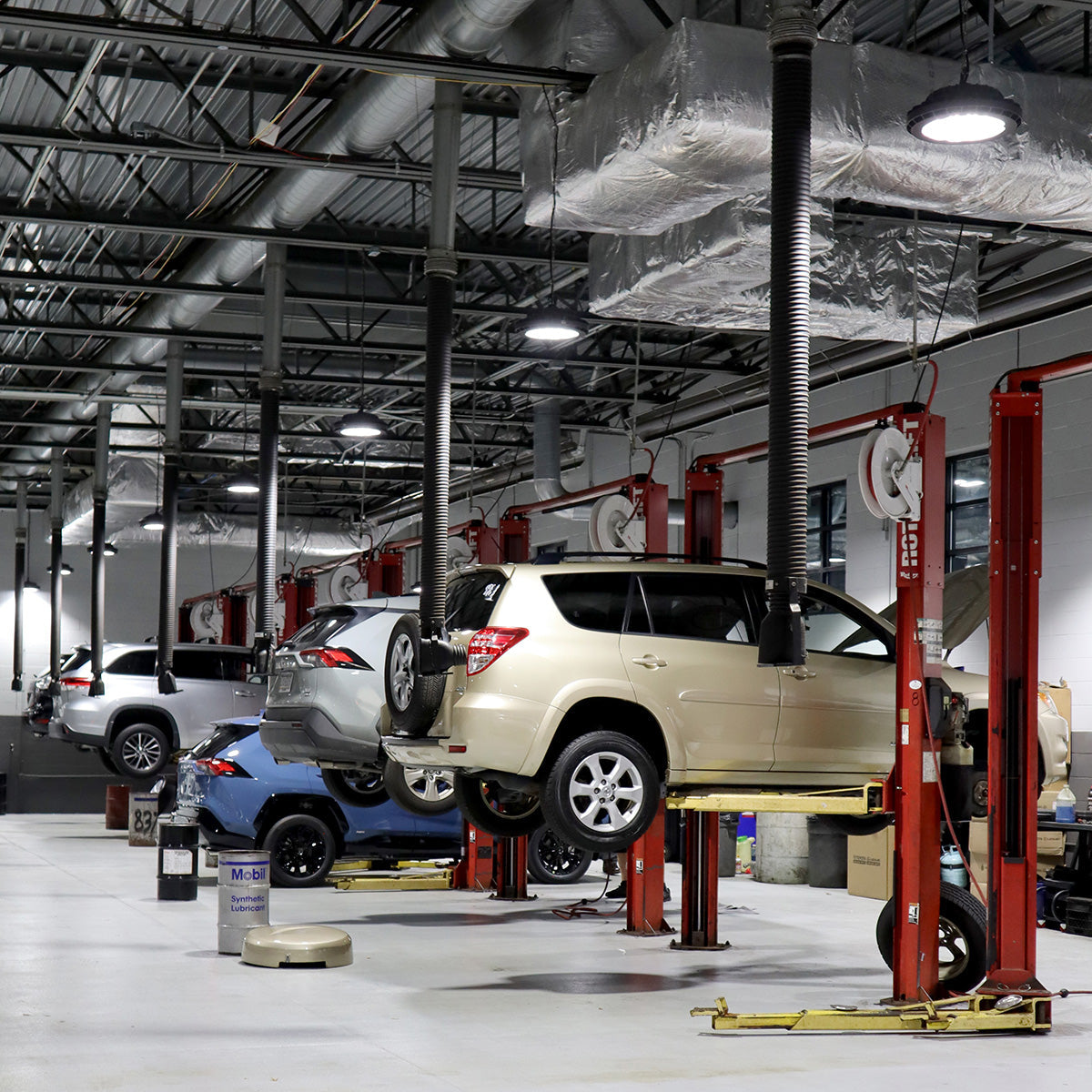 UFO LED Low Bay 2 CCT 100W 80W 60W lighting illuminating a clean automotive service garage with cars on lifts