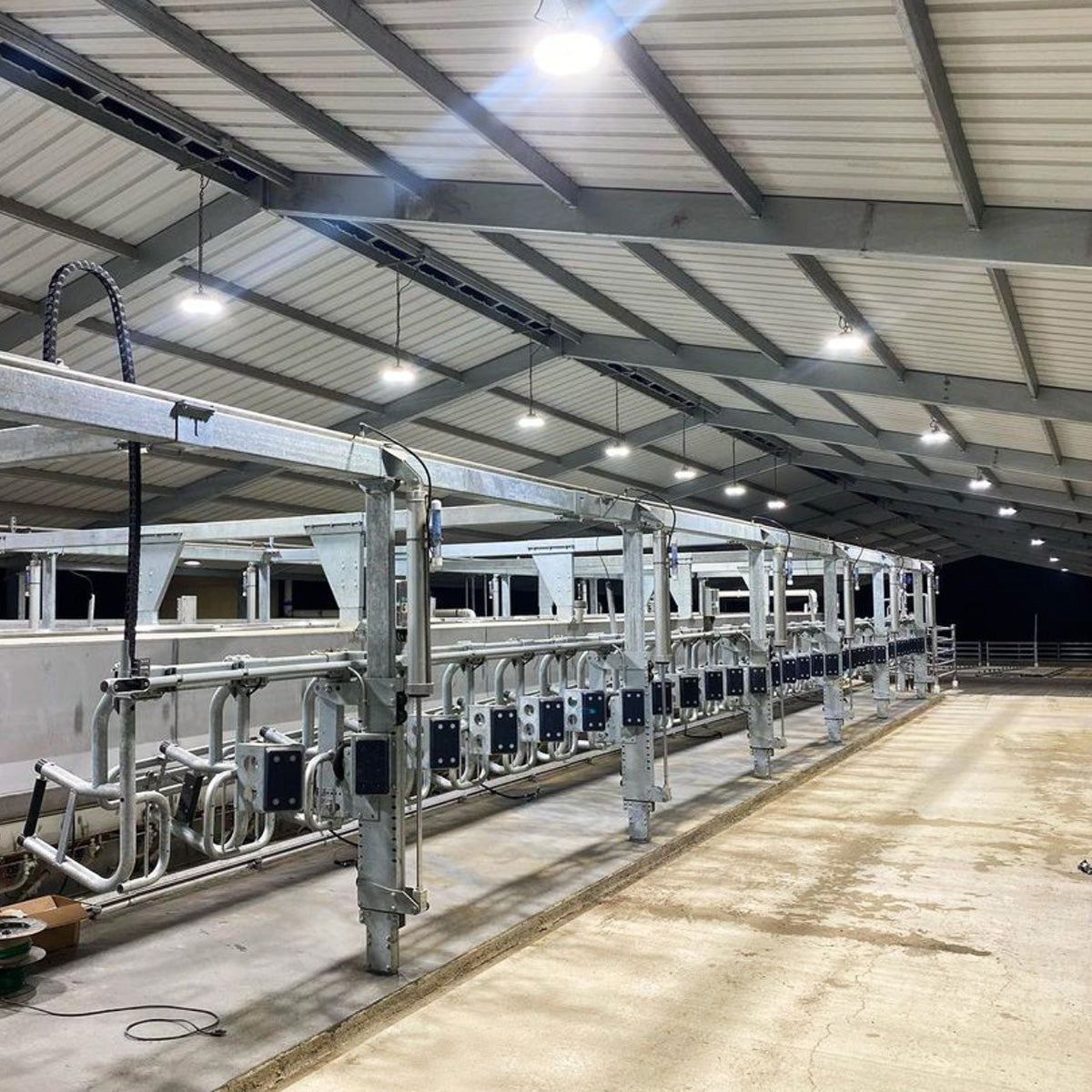 UFO LED Low Bay 2 CCT 100W 80W 60W illuminates a large industrial barn with bright, even lighting at night.