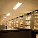1x4 Archipelago Backlit LED Panel Light - 36W installed in a library providing bright, consistent lighting above bookshelves.
