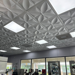 White 3D textured ceiling tiles with a geometric leaf pattern and integrated square LED light panels, installed in a salon interior.