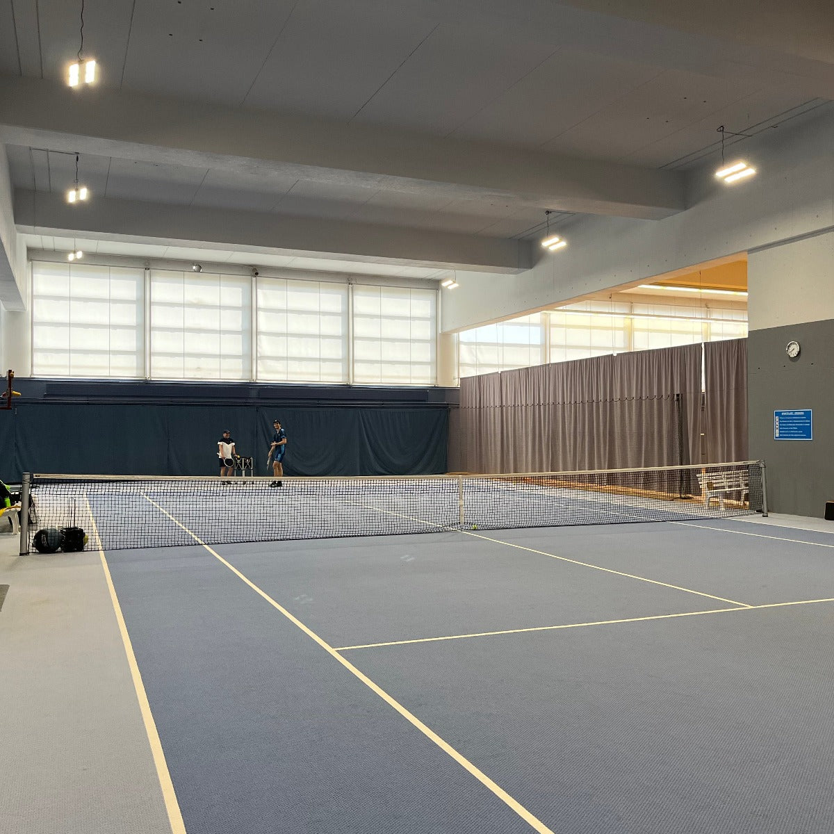 Indoor tennis court illuminated by bright Linear LED Low Bay - 90W fixtures mounted on ceiling beams