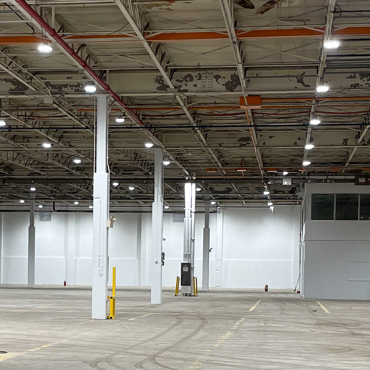 Large industrial warehouse illuminated by multiple UFO LED High Bay lights with adjustable beam angles and color temperature.