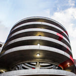 Exterior view of a circular parking garage illuminated by LED Canopy Light - 2 CCT - 60/46/36/22W fixtures at dusk