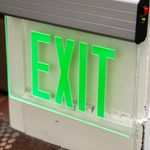 LED Edge Lit Exit Sign - MaxLite with green illuminated letters in a sleek modern thin-profile housing mounted on wall
