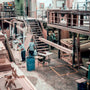 Woodworking factory interior with multiple workers handling wood pieces under industrial lighting fixtures