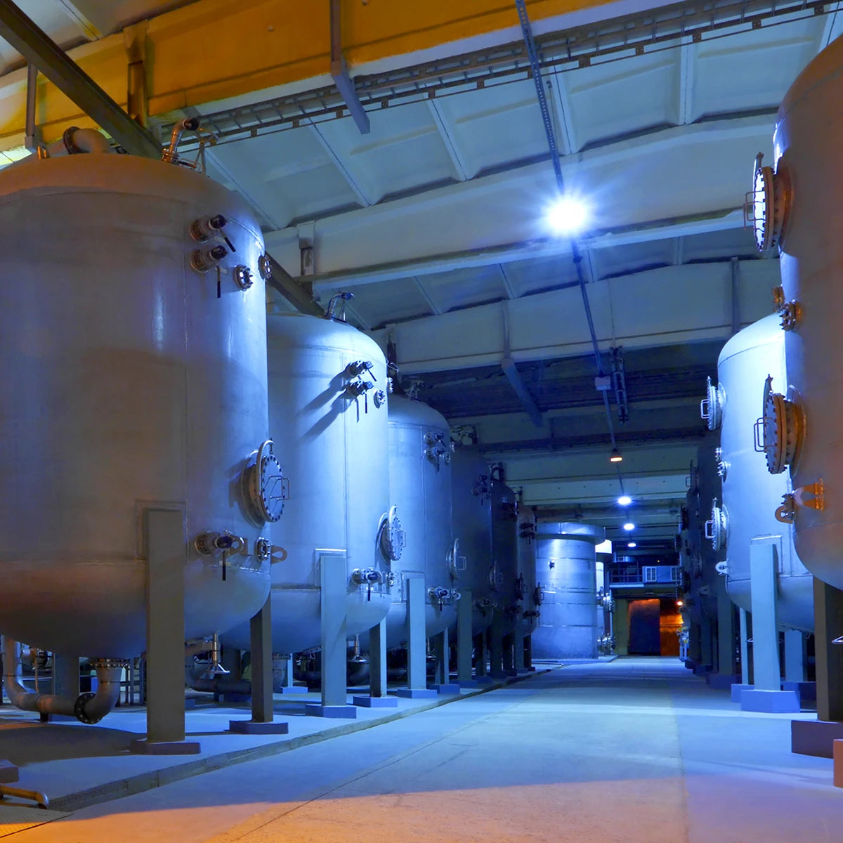 LED Hazardous Location Explosion Proof Marine Grade Light illuminating industrial tanks in a large facility at night