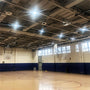 Empty indoor basketball court with high ceiling lights and multiple basketball hoops along the walls