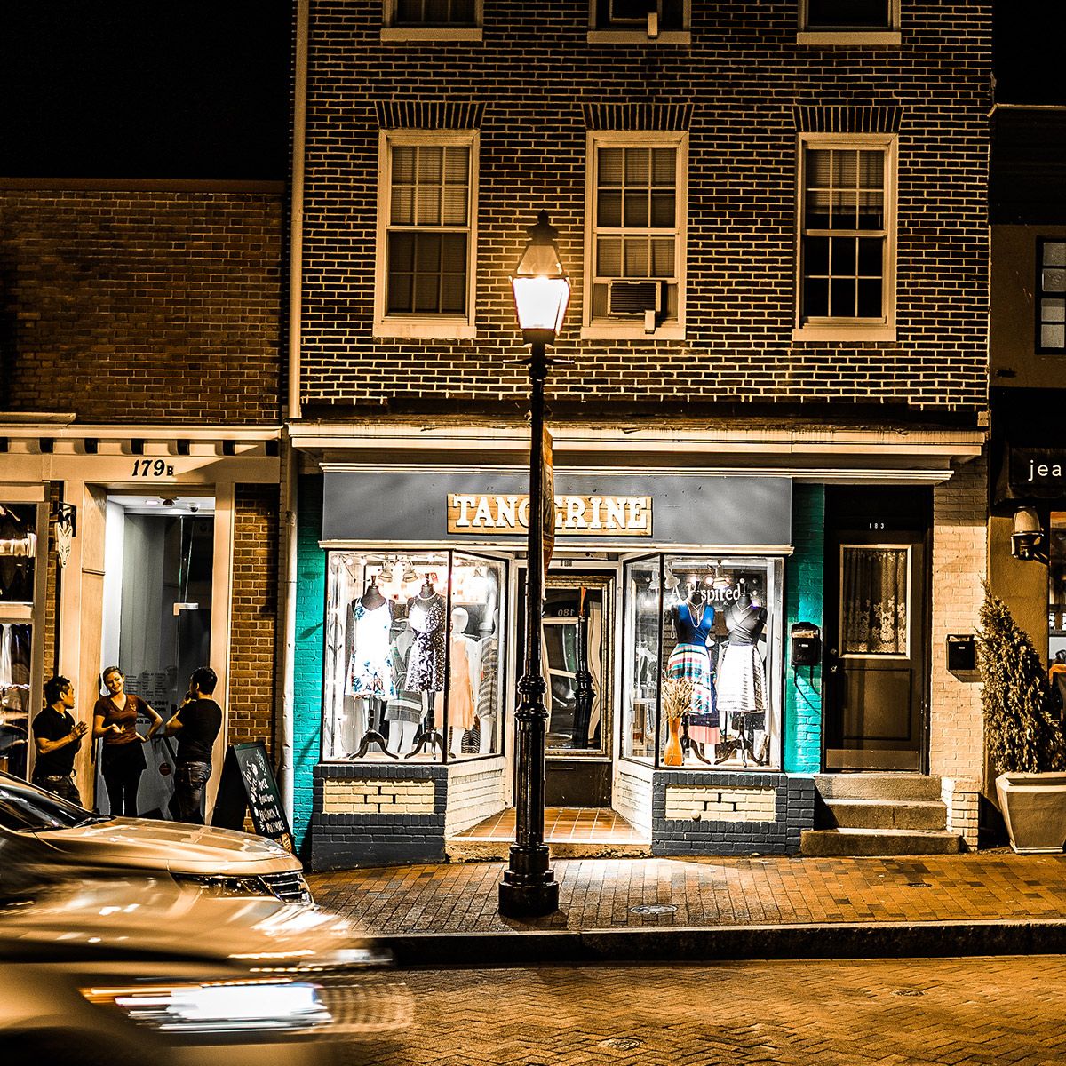 LED Bollard Retrofit - 3 CCT - 18W installed on a streetlight illuminating a brick building facade at night