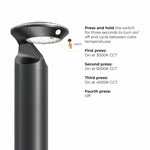 A black outdoor landscape light with a circular head and LED panel, shown next to text explaining how to press and hold the switch to turn it on/off and cycle through color temperatures.