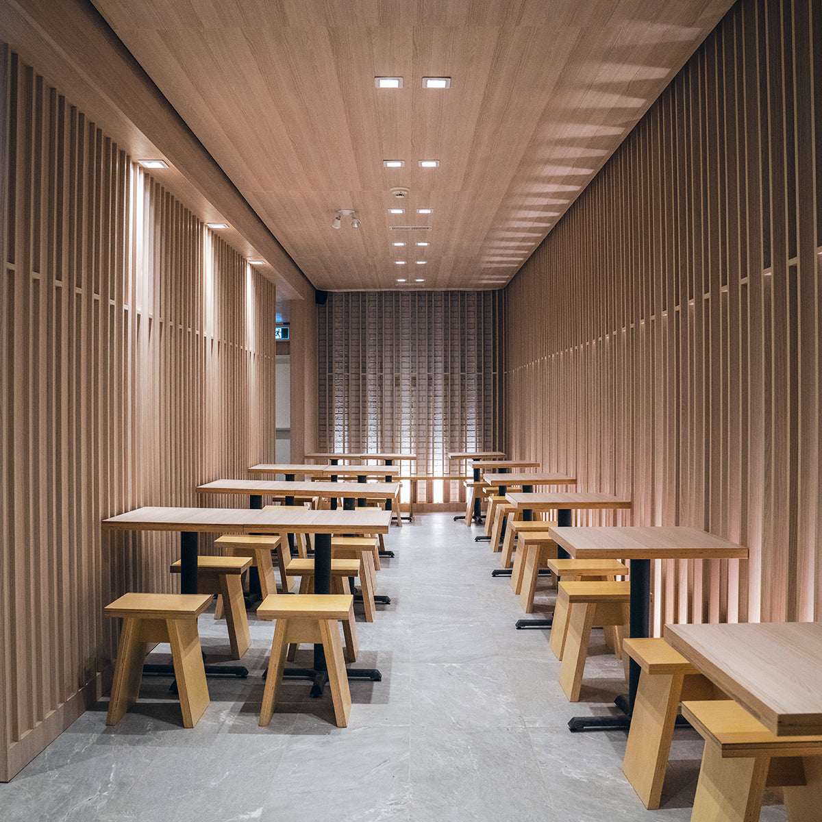 Modern dining area with wooden tables and stools, illuminated by 6" Square LED Downlight - 5-CCT - 13.5W - Nora FLIN E