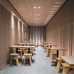 Modern dining area with wooden tables and stools, illuminated by 6" Square LED Downlight - 5-CCT - 13.5W - Nora FLIN E