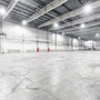 Interior view of a large industrial warehouse illuminated by bright UFO LED High Bay 3-CCT MaxLite Eco Gen 3 lights