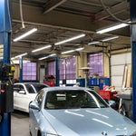 Bright 8ft LED Tube 42W R17D HO lights installed in high ceiling auto repair shop with cars and equipment.