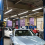 Bright 8ft LED Tube 42W R17D HO lights installed in high ceiling auto repair shop with cars and equipment.