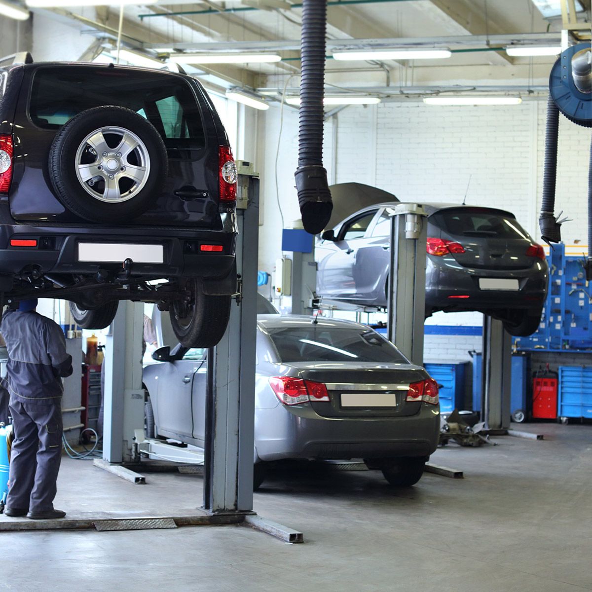 Car repair garage with vehicles on lifts illuminated by bright 2ft LED shop lights with adjustable brightness and color temperature
