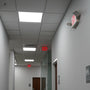 LED Exit Sign & Emergency Light Combo mounted on hallway wall illuminating exit path in an office setting