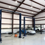 UFO LED High Bay 135W lights illuminate a spacious automotive workshop with modern car lifts and vehicles.