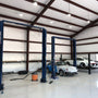 UFO LED High Bay 135W lights illuminate a spacious automotive workshop with modern car lifts and vehicles.