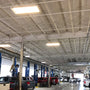480W LED Linear High Bay Panel lighting brightens a spacious industrial garage with high ceilings and parked trucks.
