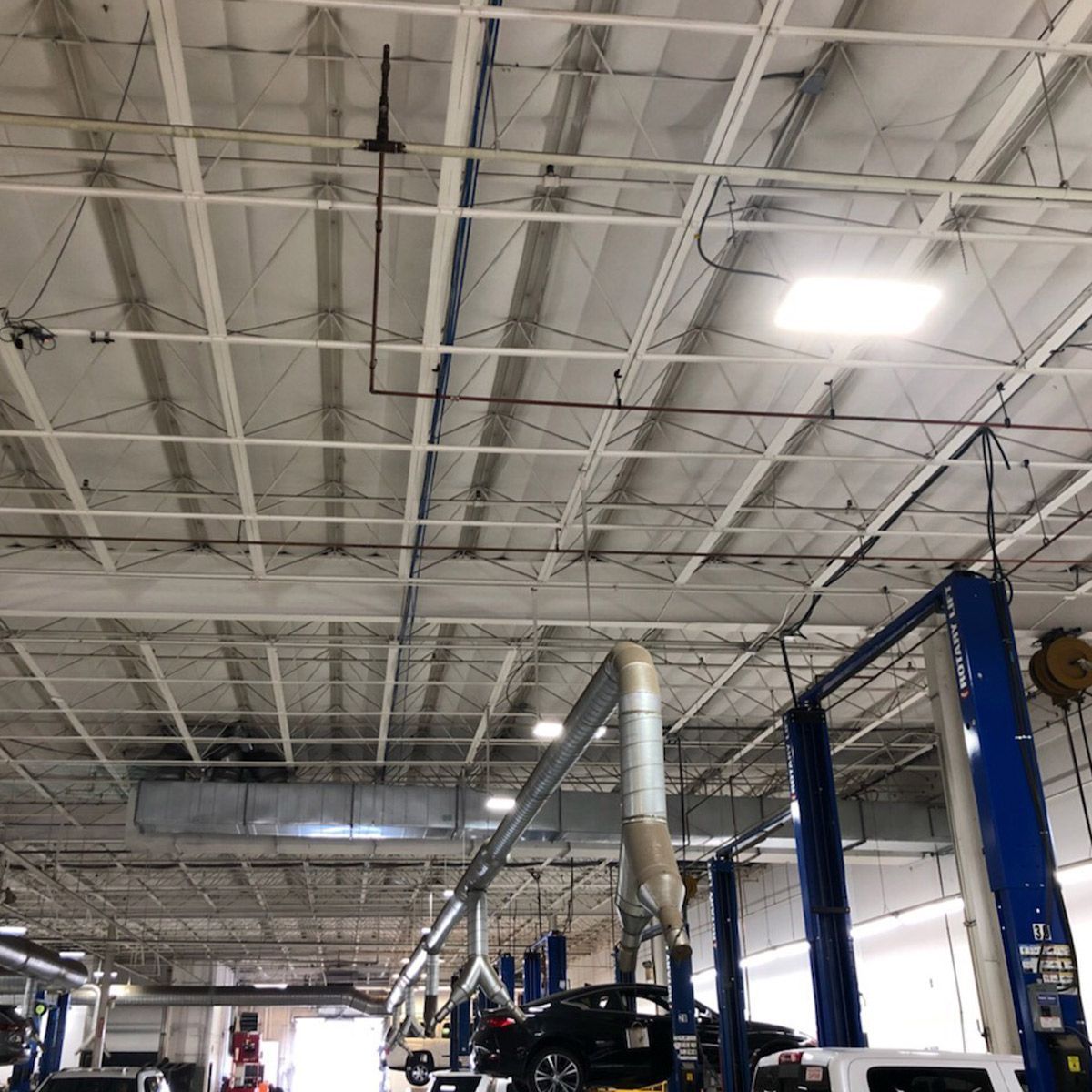 480W LED Linear High Bay Panel lighting a large industrial garage with bright white light from the ceiling fixtures