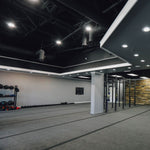 Modern gym interior illuminated by multiple 90W High Lumen Dimmable LED Low Bay Fixtures mounted on the ceiling