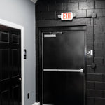 LED Exit Sign and Emergency Light Combo mounted above black exit door with emergency lights on each side