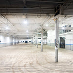Spacious industrial warehouse brightly illuminated by Value UFO LED High Bay lights mounted on the ceiling beams.